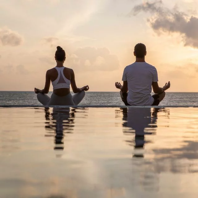 Couple meditating at sunset